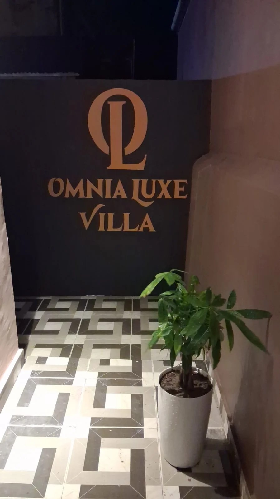 Back-lit Omnia Luxe Villa entrance sign with geometric tiles
